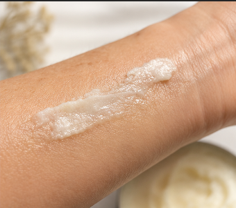 Close-up of a hand with a small amount of cream applied on a neutral background