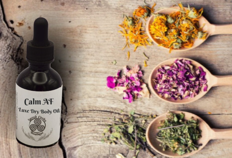 Bottle of Calm AF Luxe Dry Body Oil with dried flowers and herbs on a wooden surface
