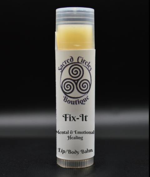 Lip/body balm tube labeled 'Fix-It' from Sacred Circles Boutique on a black background