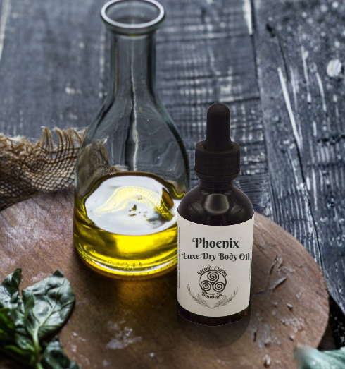Bottle of Phoenix Luxe Dry Body Oil on a wooden surface with a glass container of oil.
