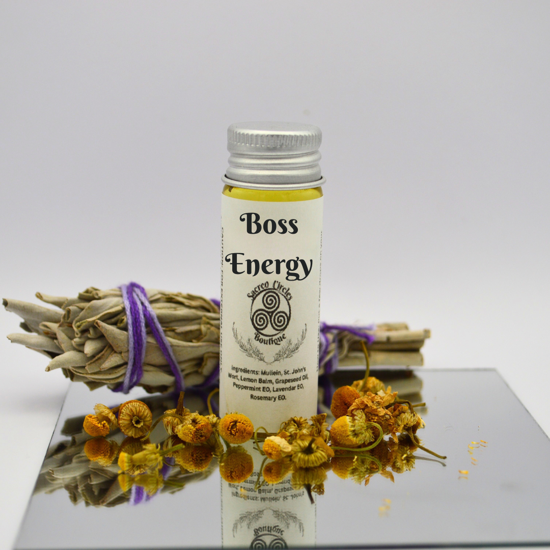 Boss Energy body oil in 15 mL with dried herbs and flowers on a reflective surface