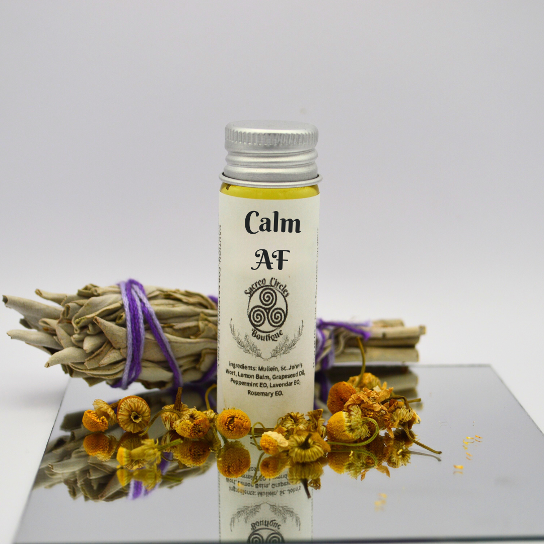 Calm AF body oil in 15 mL with dried flowers and herbs on a reflective surface