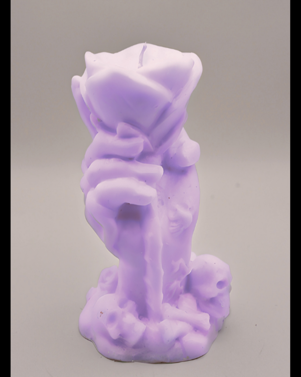 Purple candle shaped like a hand holding a rose on a gray background