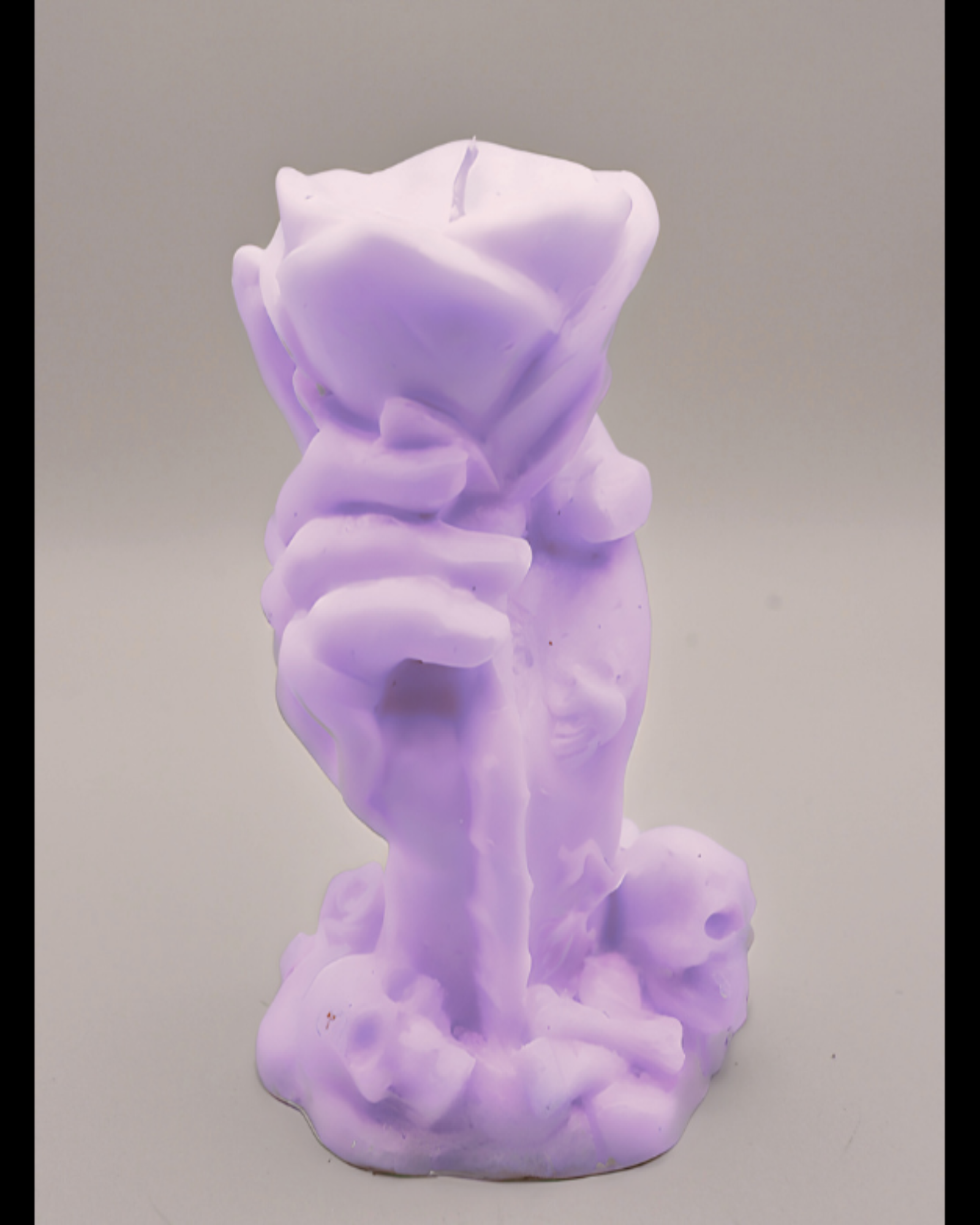 Purple candle shaped like a hand holding a rose on a gray background