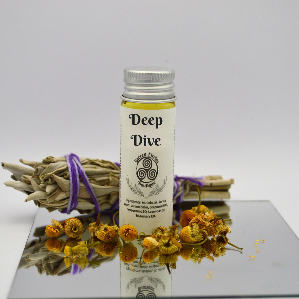 Deep Dive body oil in 15 mL with dried herbs and flowers on a reflective surface