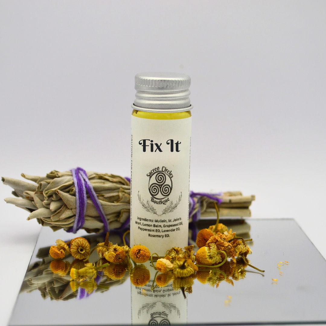 Fix It body oil in 15 mL with dried herbs and flowers on a reflective surface